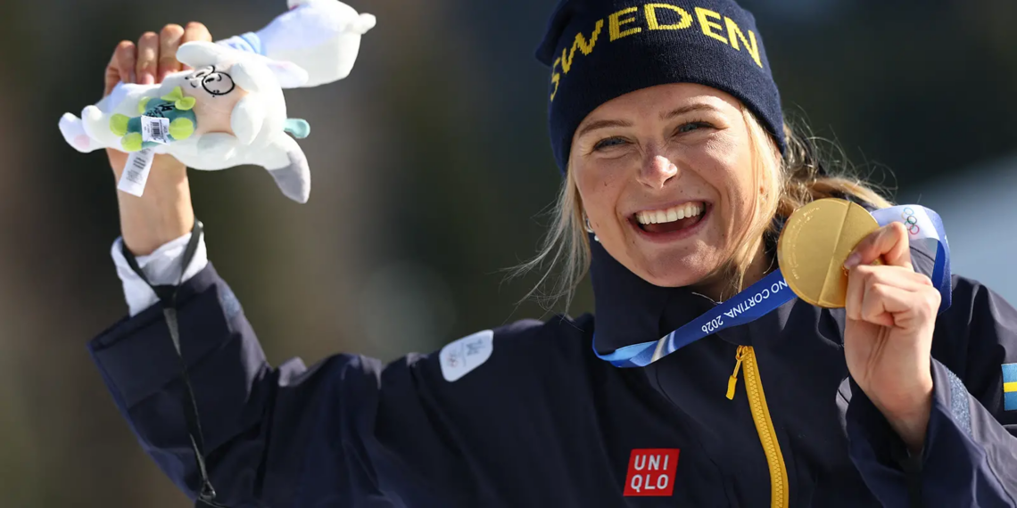 Frida Karlsson håller upp sin guldmedalj efter segern på 10 kilometer fristil vid OS 2026.