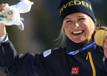 Frida Karlsson håller upp sin guldmedalj efter segern på 10 kilometer fristil vid OS 2026.